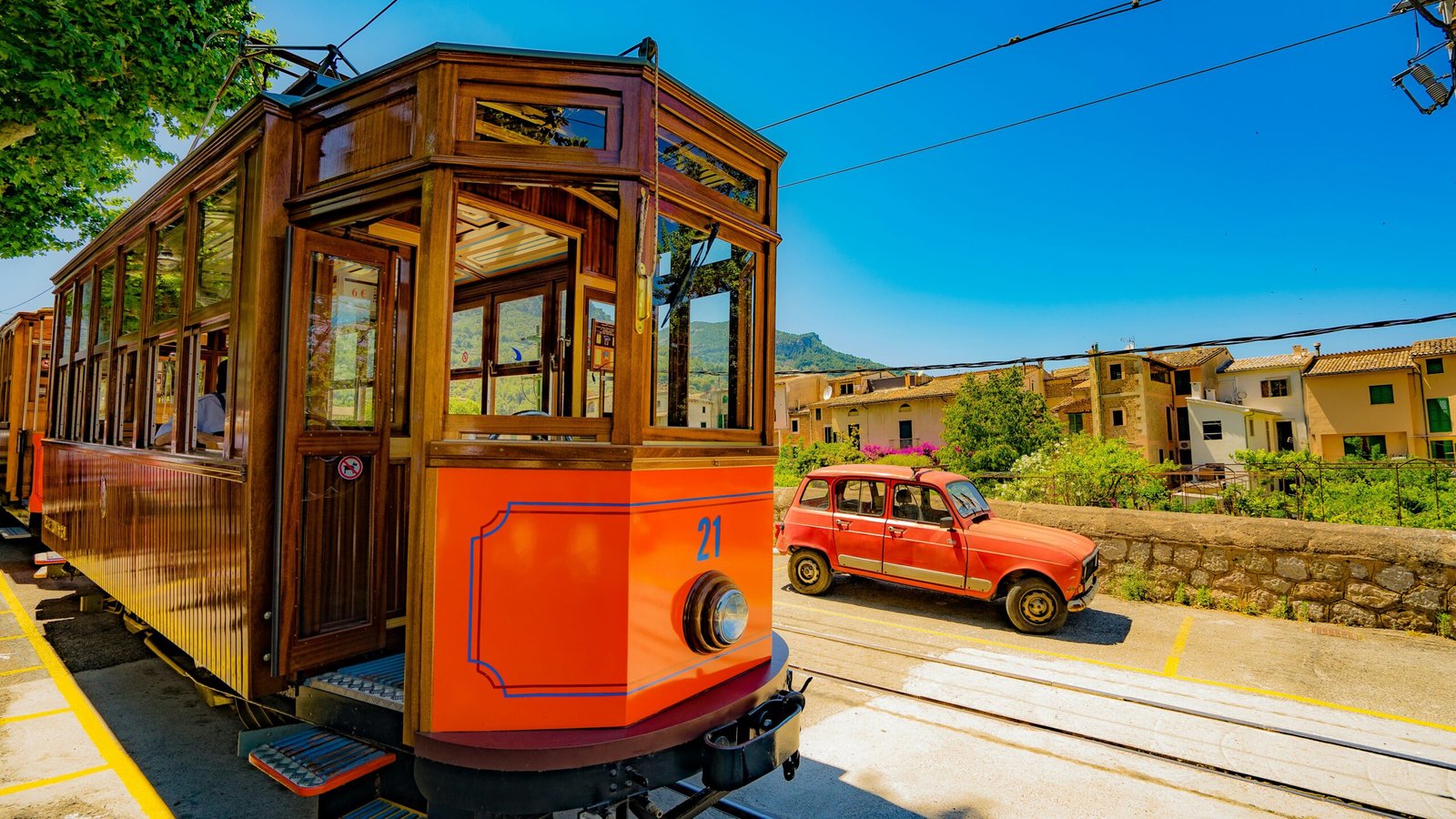 red train passing through rails beside red vehicle